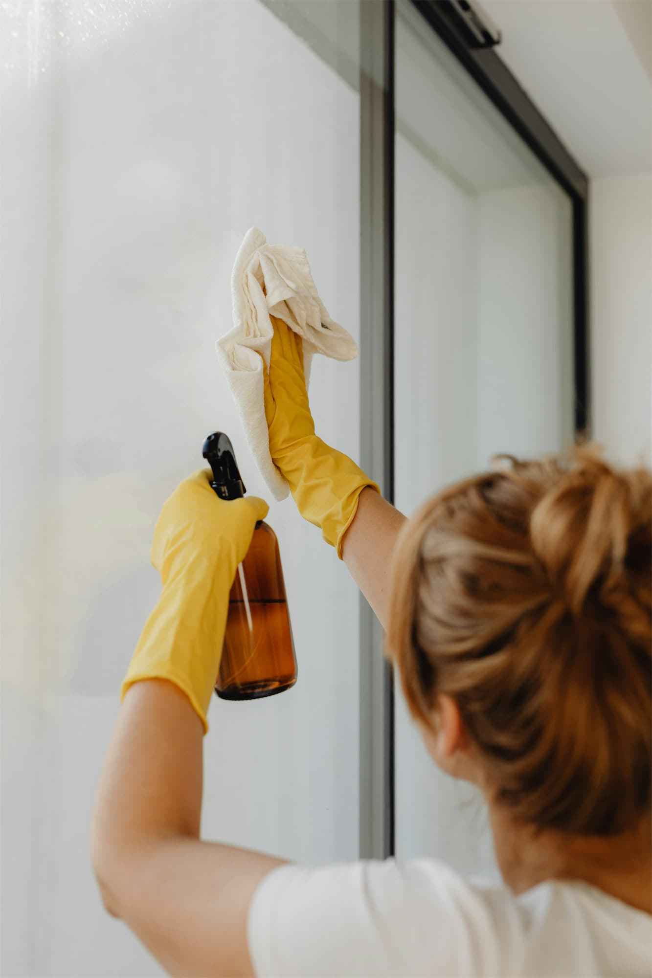 Sparkling glass being cleaned with yellow gloves and a microfiber cloth